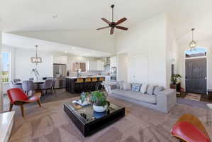 Living area featuring hanging lights, light wood-type flooring, a ceiling fan, and lofted ceiling