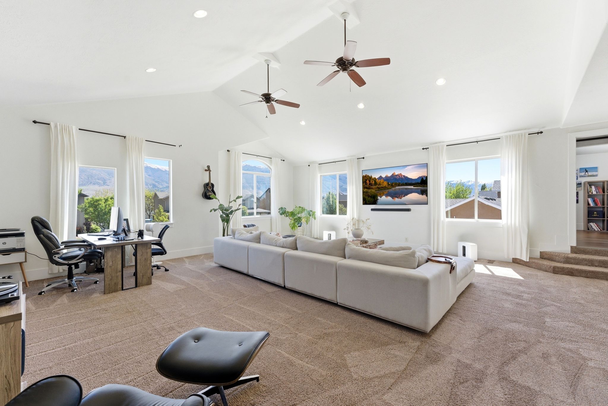 Living room with a desk, light carpet, a high ceiling, ceiling fan, and recessed lighting
