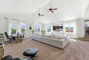 Living room with a desk, light carpet, a high ceiling, ceiling fan, and recessed lighting