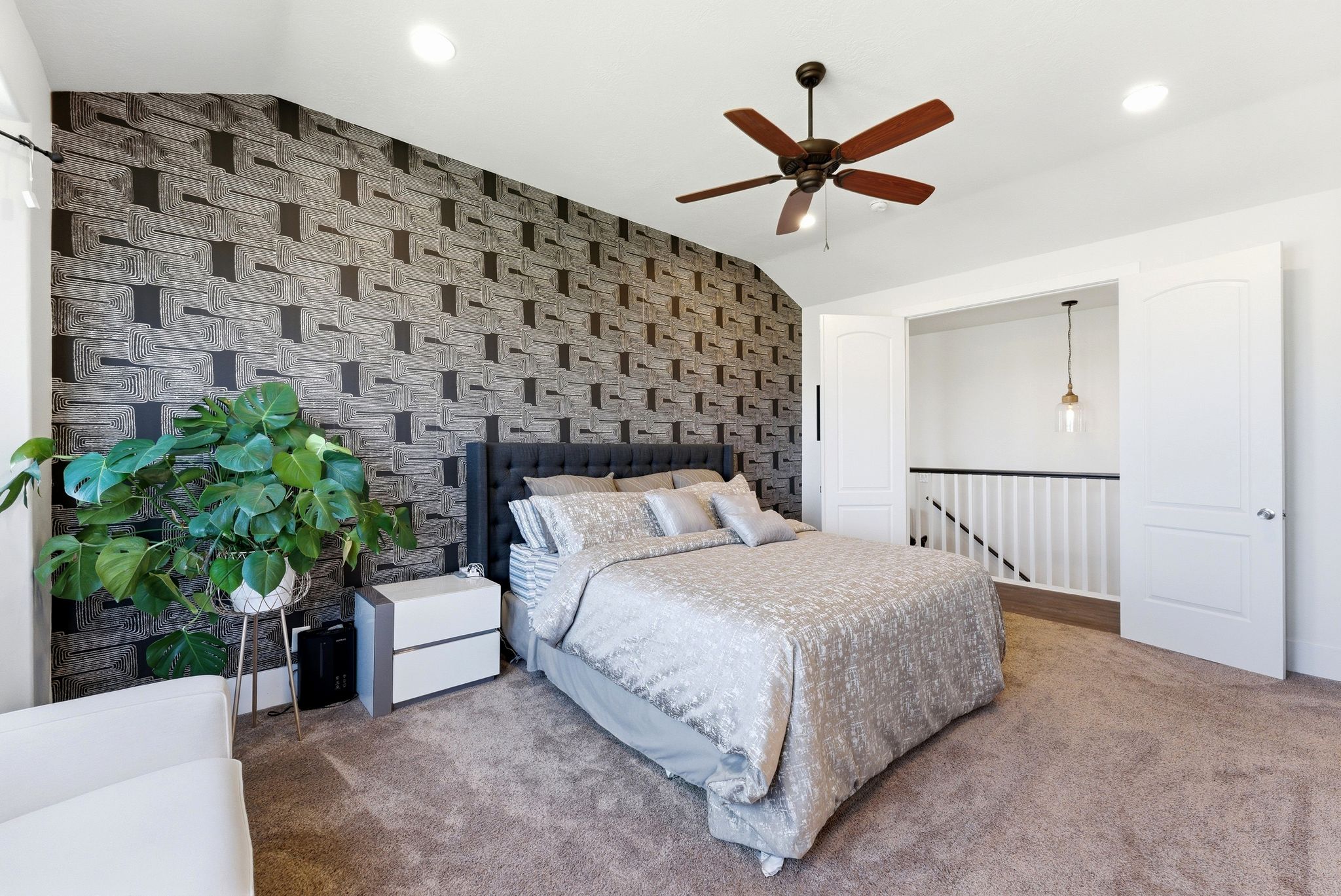 Carpeted bedroom featuring an accent wall, lofted ceiling, wallpapered walls, and a ceiling fan