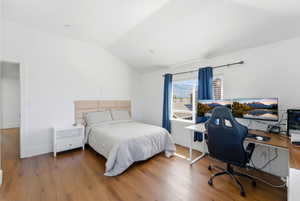Bedroom featuring vaulted ceiling, a desk, and hardwood / wood-style floors