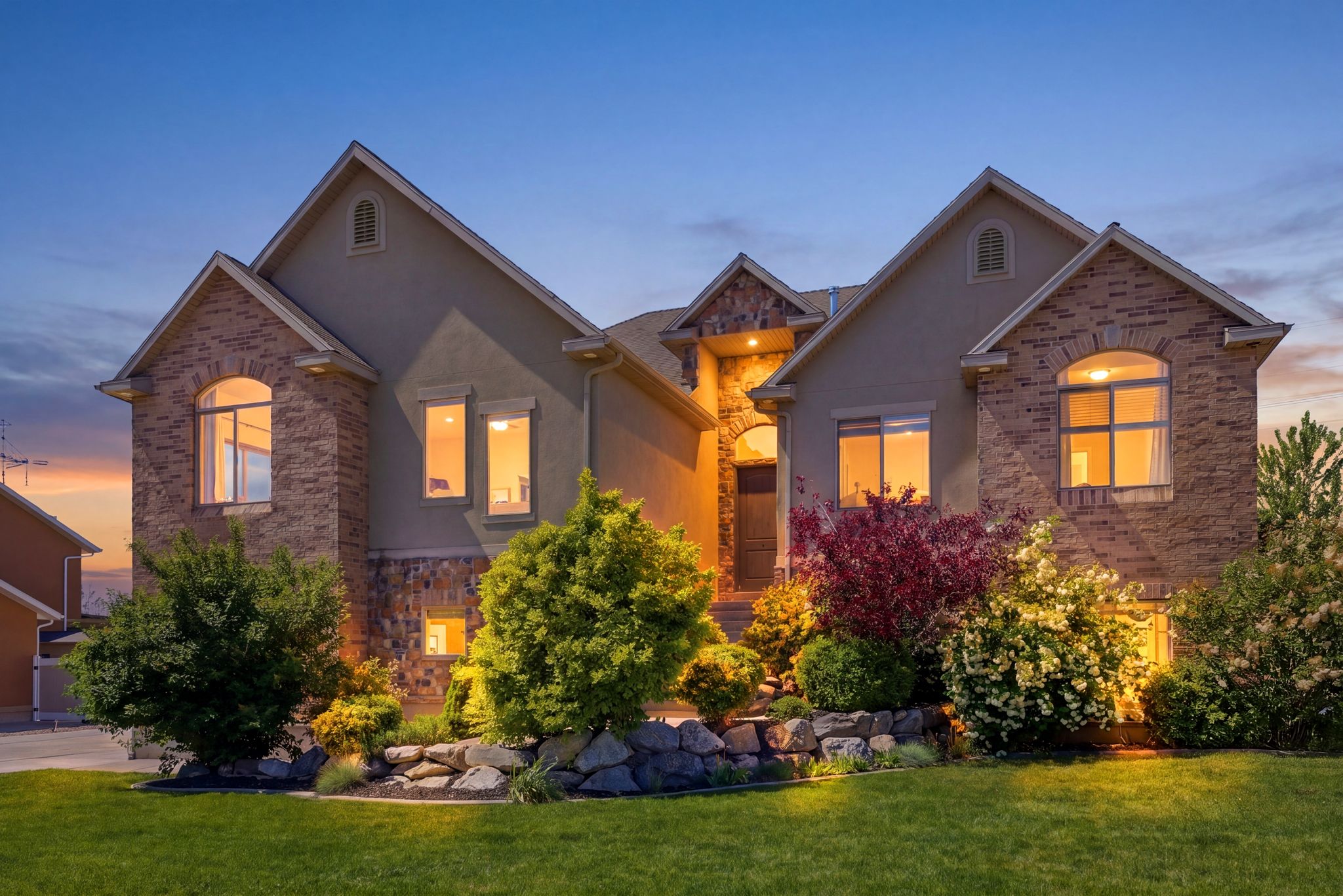 Traditional-style home with stucco siding, a front yard, and stone siding