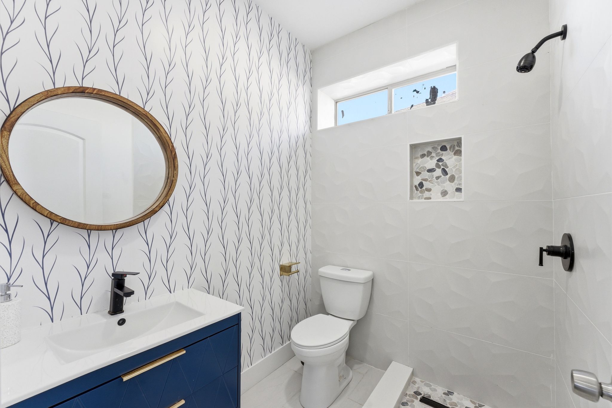 Full bathroom featuring vanity, tiled shower, and wallpapered walls