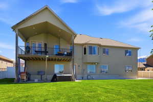 Rear view of property with stucco siding, a patio area, and a hot tub