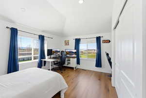 Bedroom with a desk, vaulted ceiling, and light wood finished floors