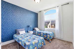 Carpeted bedroom featuring an accent wall and wallpapered walls