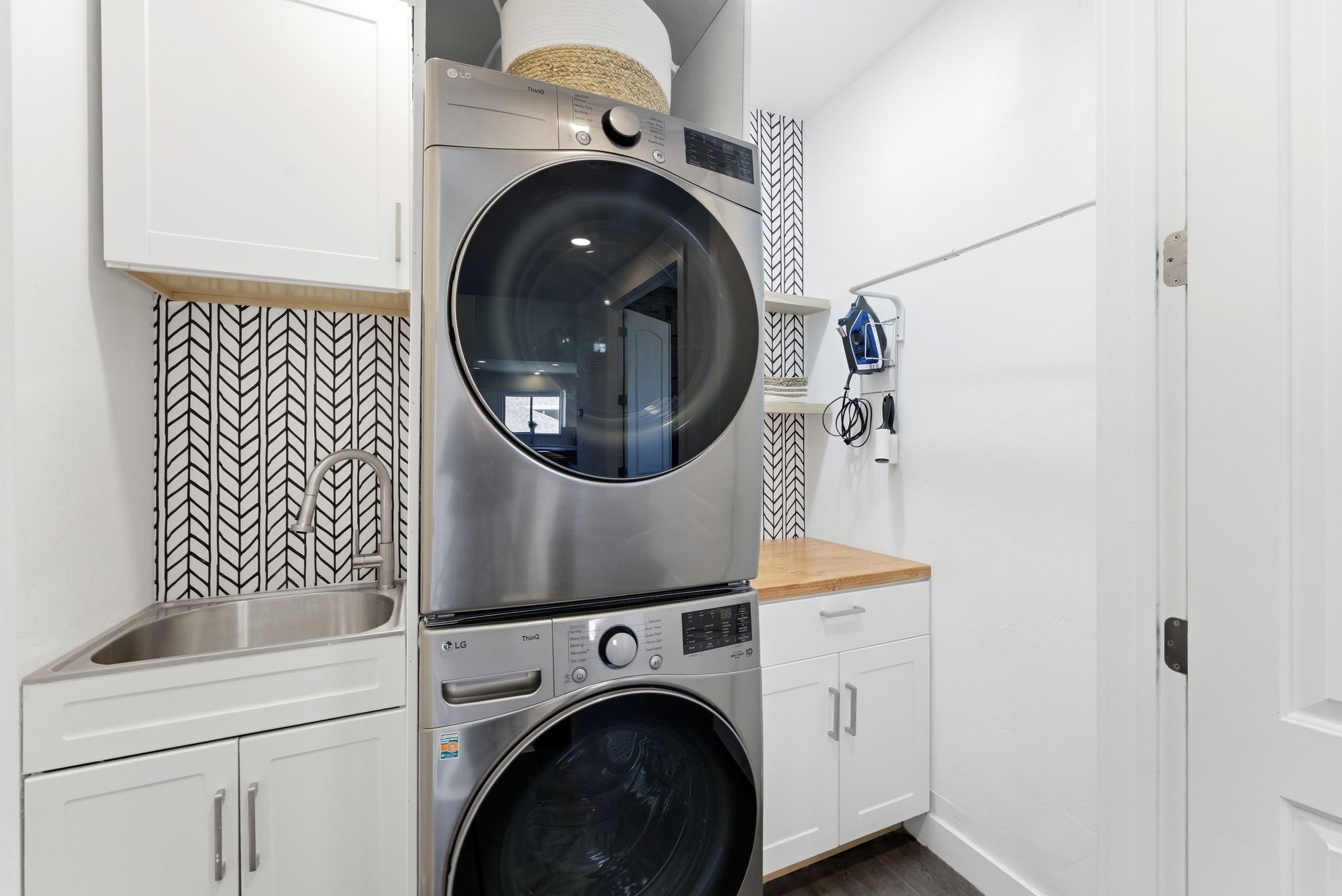 Laundry area featuring cabinet space, stacked washer and clothes dryer, and dark wood-type flooring