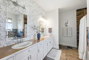 Bathroom with double vanity, dark stone finish flooring, a bath, and a shower with curtain