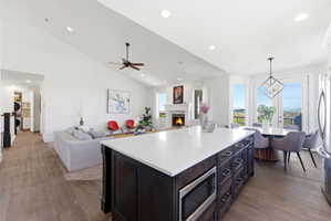 Kitchen featuring open floor plan, dark wood finished floors, a kitchen island, stainless steel appliances, and lofted ceiling