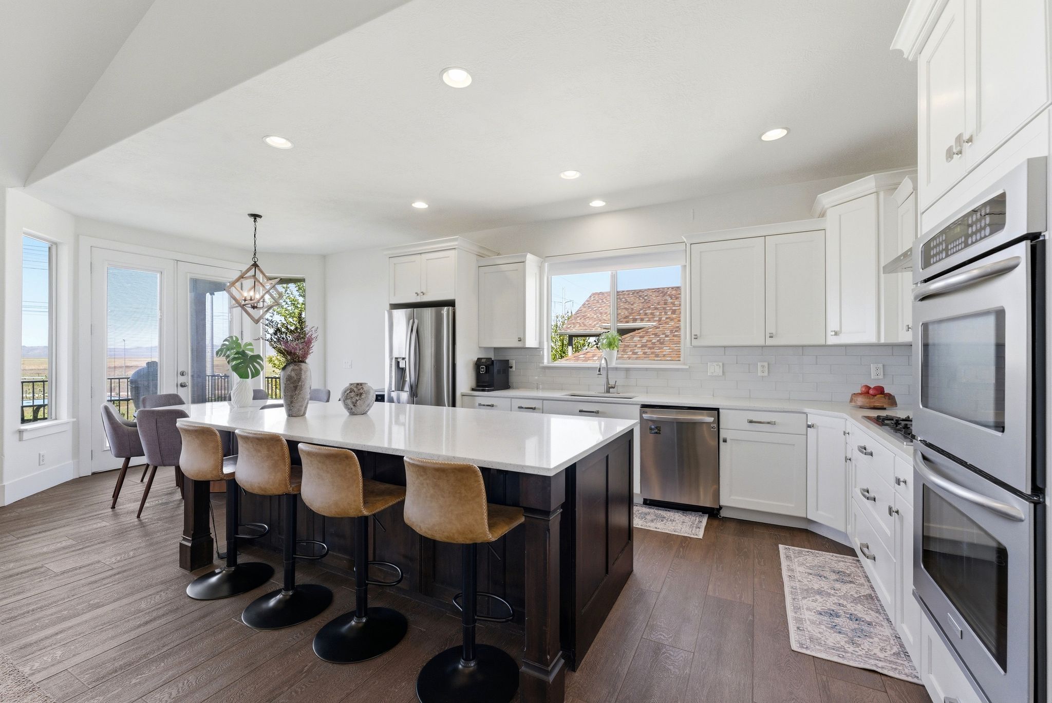 Kitchen with dark wood-style flooring, stainless steel appliances, a kitchen island, two tone cabinetry, and a breakfast bar