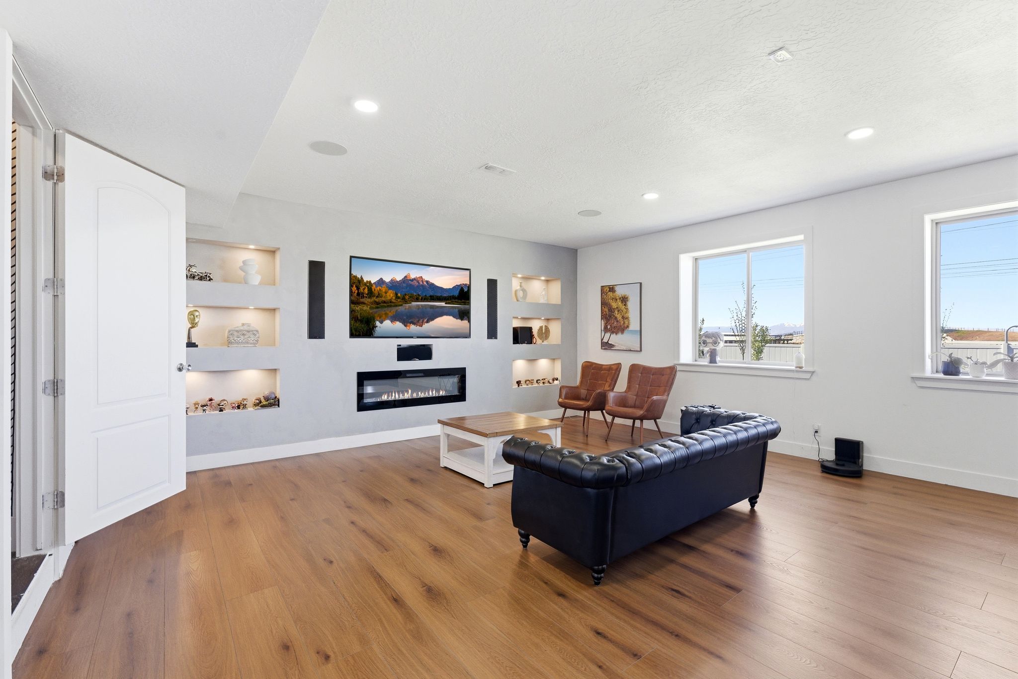 Living room featuring built in features, a glass covered fireplace, light wood-type flooring, and recessed lighting