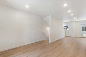 Open-concept living area featuring light wood-finish flooring, recessed ceiling lighting, and a neutral color palette