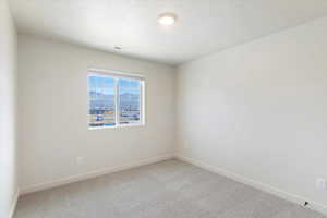 Bright room featuring a large window with horizontal blinds, neutral wall paint, gray carpet flooring, and a ceiling-mounted light fixture