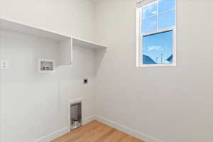 Dedicated laundry space featuring wood-finish flooring, white walls, and built-in shelving