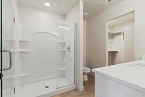Contemporary bathroom featuring a glass-enclosed shower with integrated shelving, a white single-basin vanity with a light-toned countertop, and recessed lighting