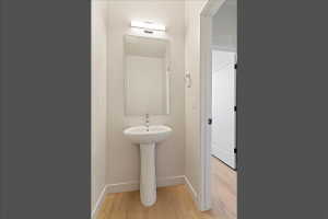 Pedestal sink with chrome faucet, framed mirror, and contemporary light fixture