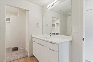 Bathroom featuring a double vanity with white cabinetry, integrated sink, and a large wall-mounted mirror