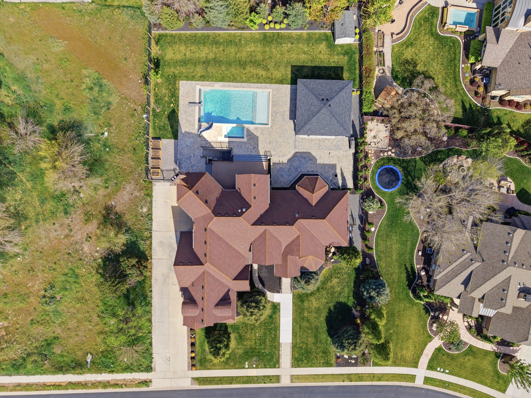 Expansive property featuring a multi-gabled main residence, a large swimming pool with surrounding patio, a poolside cabana, a well-maintained lawn, and mature landscaping