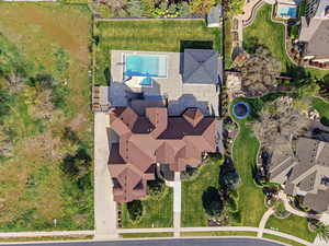 Expansive property featuring a multi-gabled main residence, a large swimming pool with surrounding patio, a poolside cabana, a well-maintained lawn, and mature landscaping