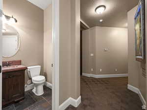 Powder room featuring a dark wood-finish vanity with a red-hued countertop, oval mirror, and slate-finish floor tiles
