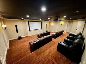 Dedicated home theater featuring a large projection screen, recessed lighting, wall sconces, and multi-tiered seating
