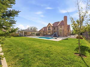 Expansive green lawn with a large in-ground swimming pool and adjacent stone-clad cabana