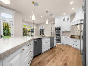 Spacious kitchen featuring white cabinetry, light-toned countertops, and wood-finish flooring