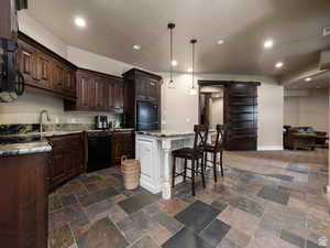 Apartment Kitchen featuring varied-tone slate flooring, dark wood cabinetry, and a light-toned countertop with an undermount sink