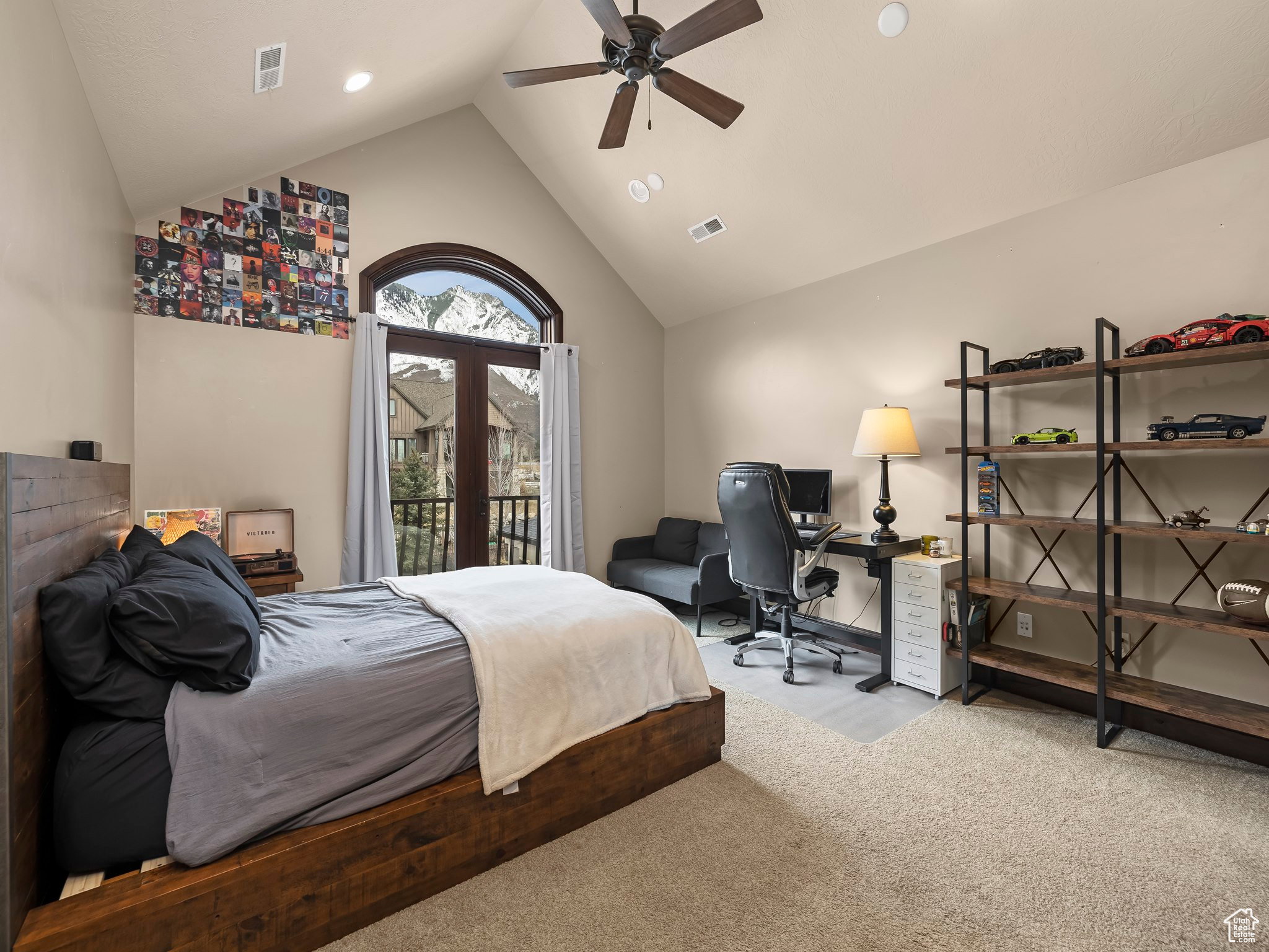 Vaulted ceiling with a ceiling fan, arched double doors opening to a balcony, light-toned wall finishes, recessed lighting, and soft carpet flooring