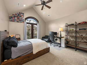 Vaulted ceiling with a ceiling fan, arched double doors opening to a balcony, light-toned wall finishes, recessed lighting, and soft carpet flooring