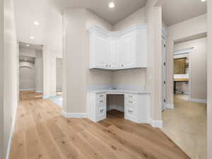 Built-in corner desk featuring white cabinetry, gold-finish hardware, and a light-toned countertop