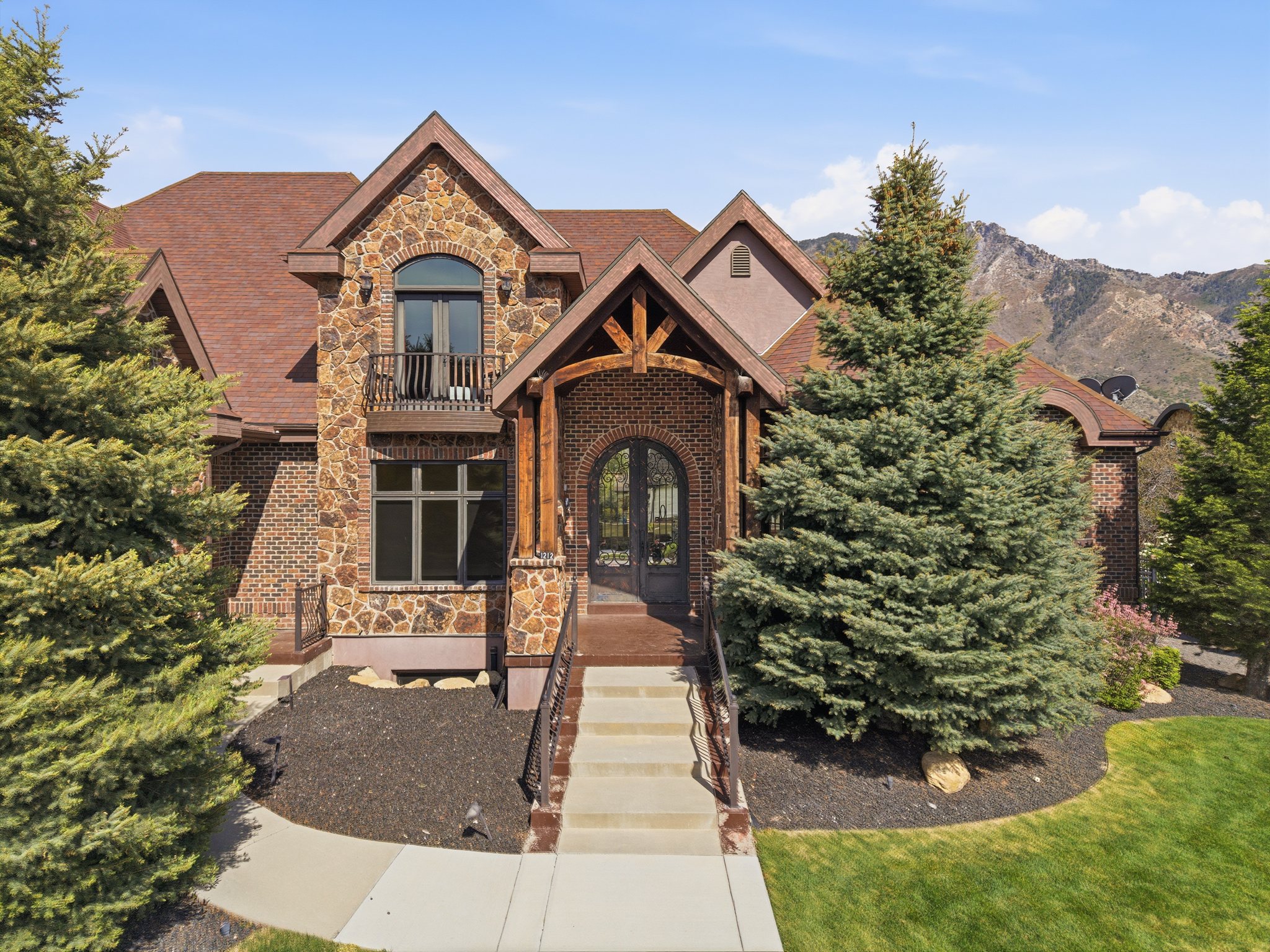 Exterior stone and brick residence featuring a prominent covered entry with wood beam accents