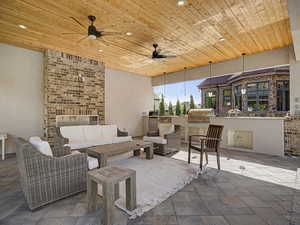 Covered outdoor living space featuring a wood plank ceiling with recessed lighting and ceiling fans