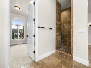 Walk-in shower featuring varied-size floor-to-ceiling brown tilework