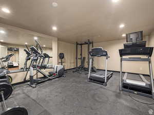 Dedicated fitness space featuring resilient black flooring, a full-wall mirror, recessed ceiling lighting, and neutral wall tones