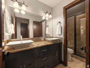 Dual vessel sinks set atop a stone countertop with dark wood cabinetry