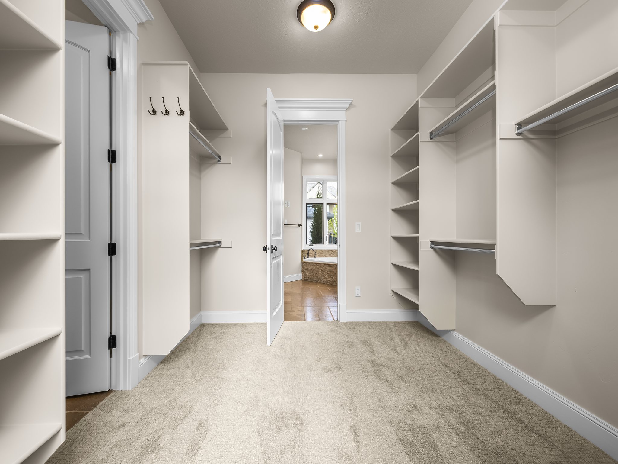 Walk-in closet featuring built-in shelving, hanging rods, light-colored carpeting, and a flush-mount ceiling light fixture