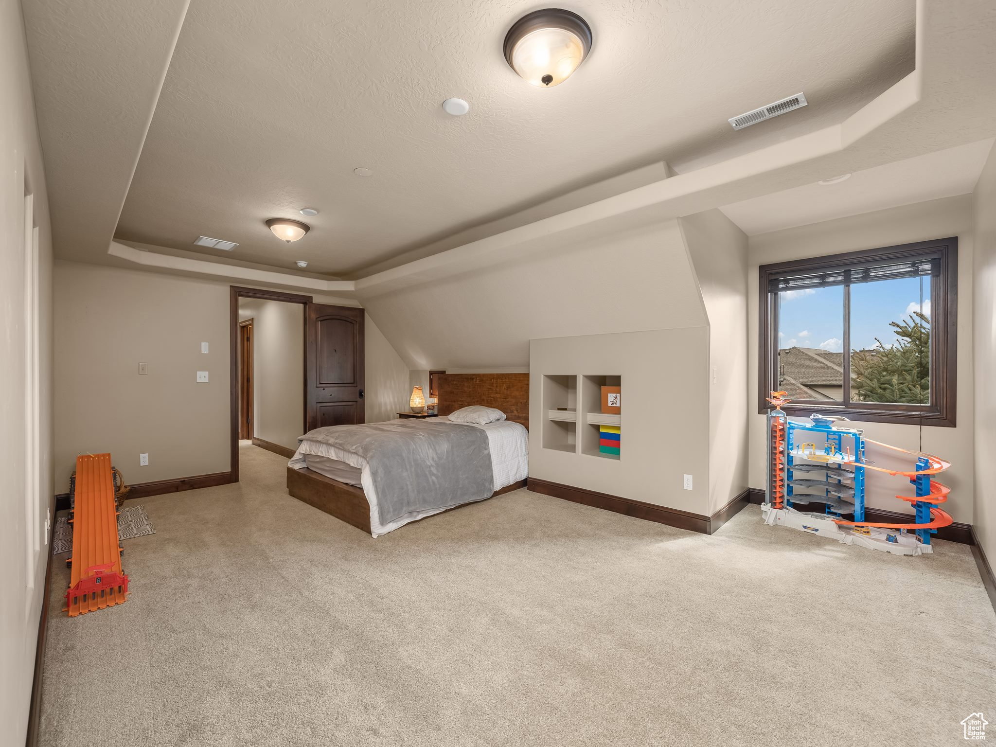 Carpeted room featuring a window with dark wood-finish trim, recessed ceiling lighting, and a built-in shelving unit