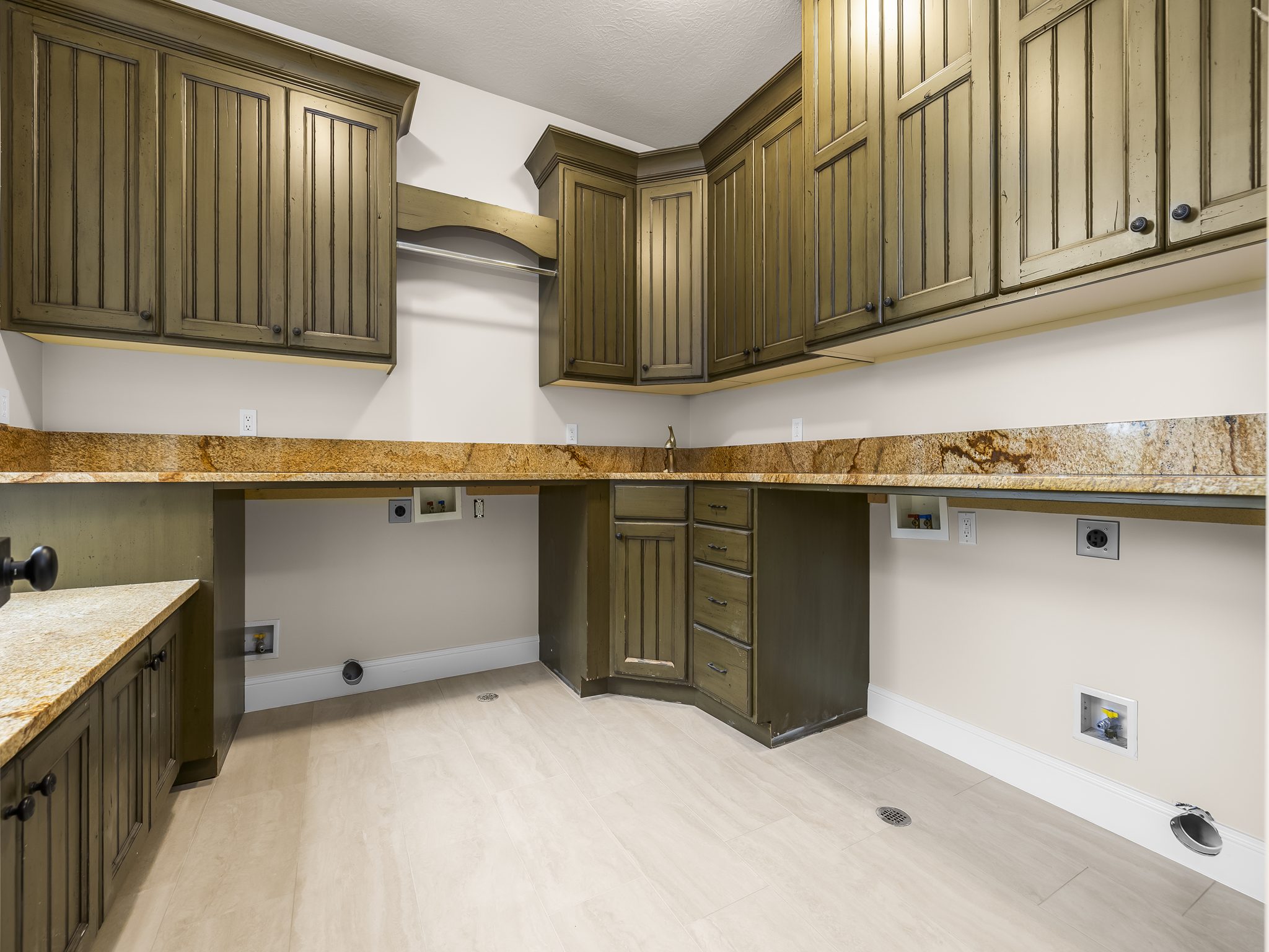 Utility room featuring extensive wood cabinetry, granite-finish countertops, wood-finish flooring, and a built-in hanging rod