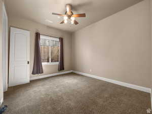 Carpeted room featuring neutral wall tones, a ceiling fan with light fixture, a window with brown drapes, and a white interior door