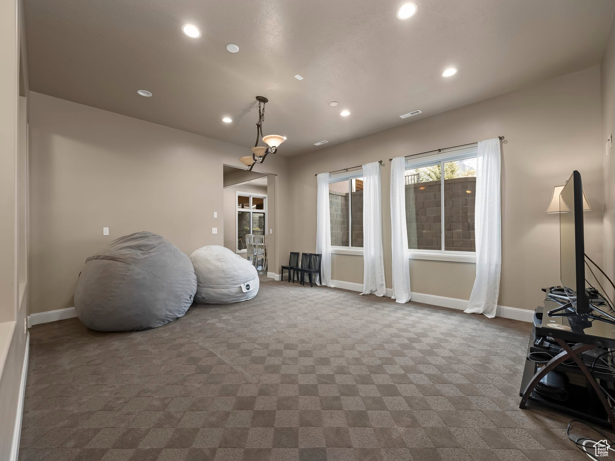 Spacious room featuring patterned carpet flooring, recessed lighting, and a multi-light chandelier