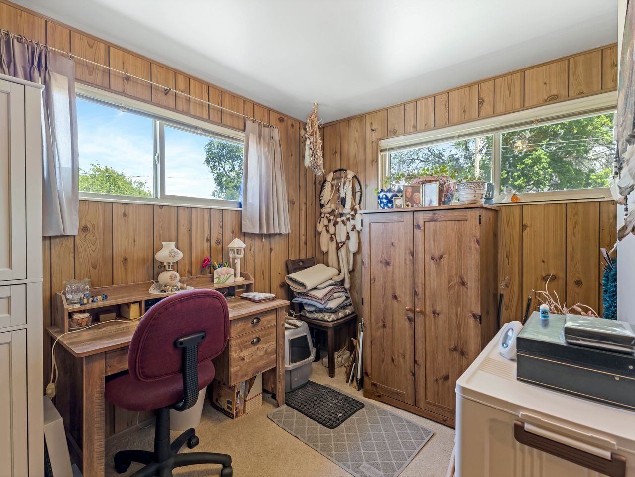 Room featuring wood paneling, two large windows, and neutral carpeting