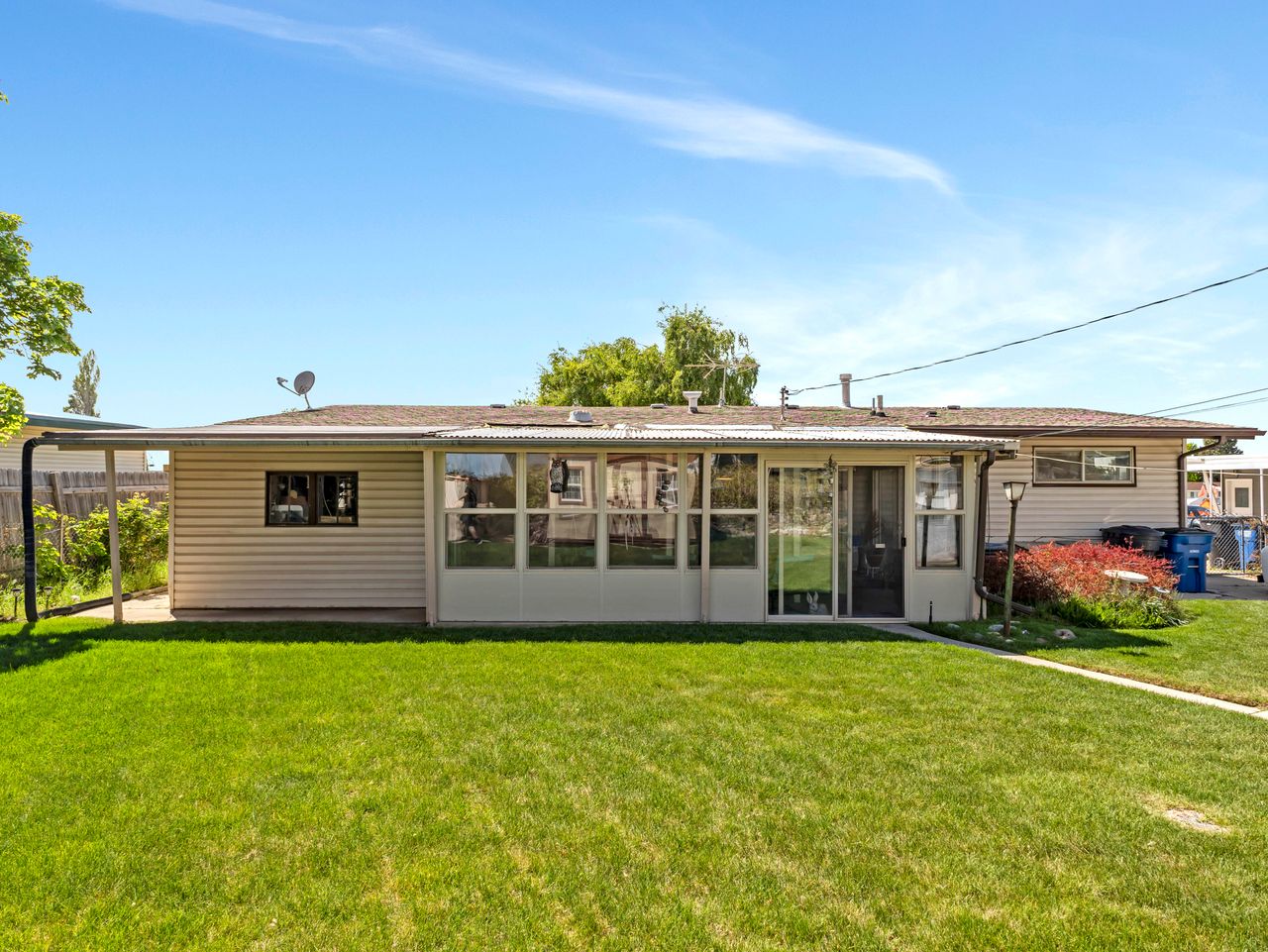 Expansive rear yard featuring a manicured lawn, an enclosed patio, and an extended covered patio