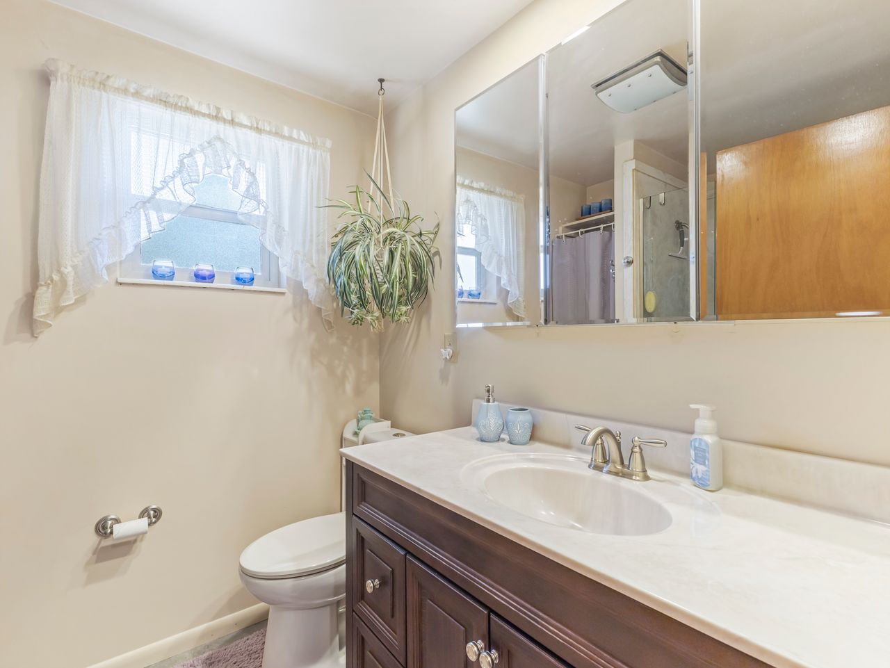 Bathroom with a dark wood-finish vanity, white countertop, and integrated sink