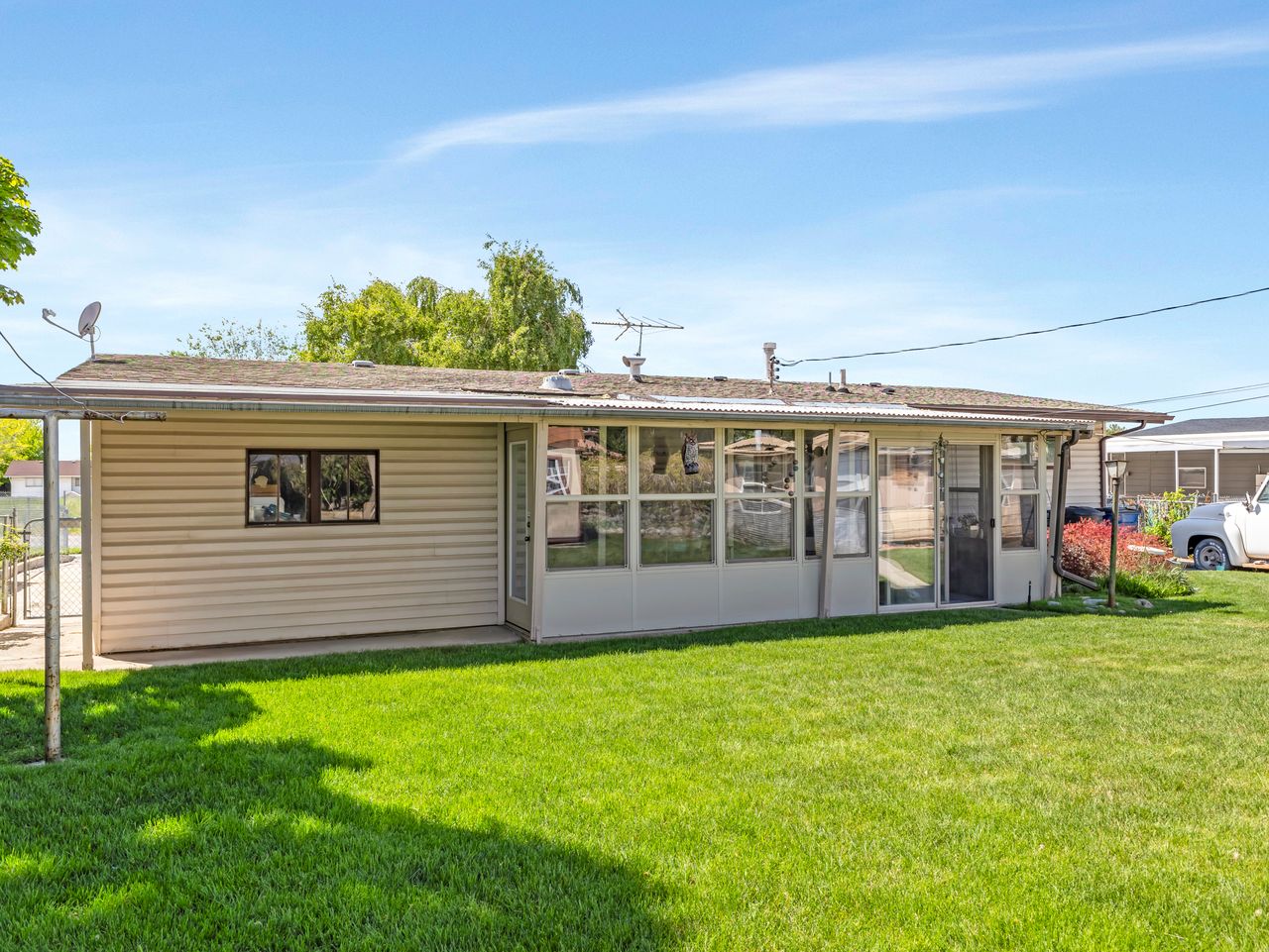 Expansive rear lawn featuring a sunroom addition with multiple windows and a storm door entry