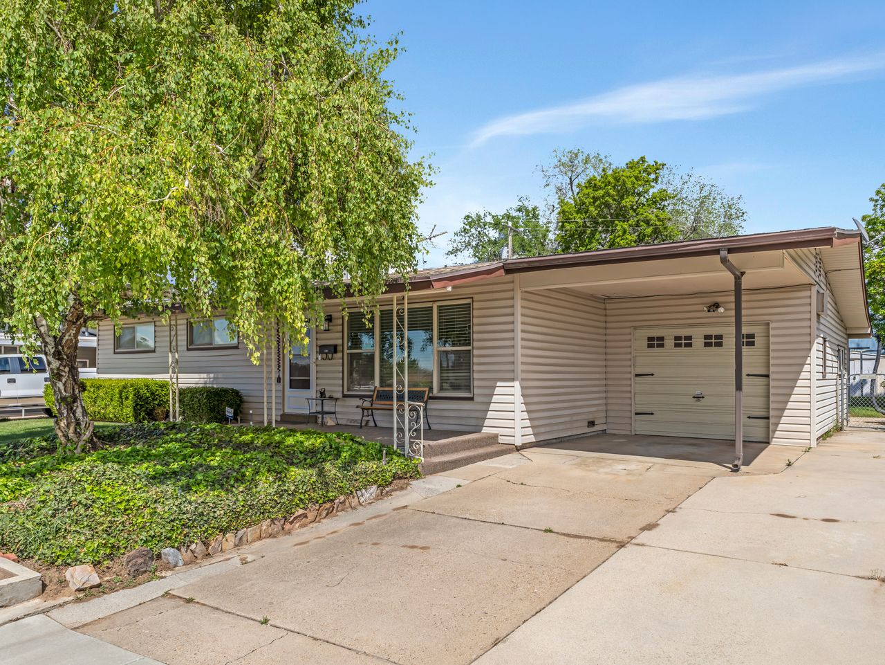 Single-story residence featuring light-toned horizontal siding, an attached single-car garage with overhead door, and a covered carport