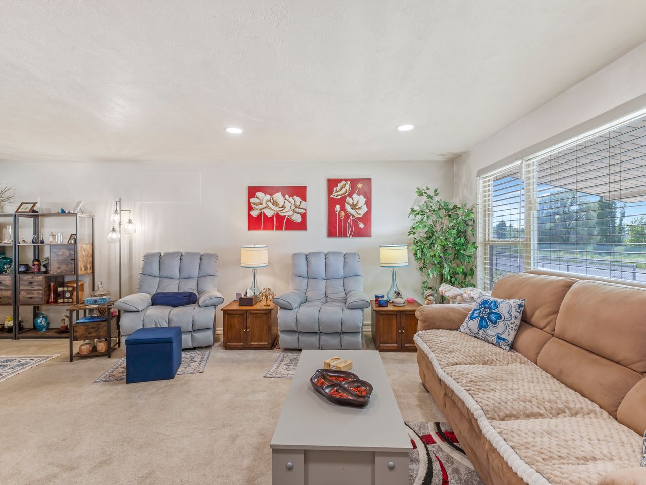 Carpeted living area featuring recessed lighting, a large window with horizontal blinds, and textured walls