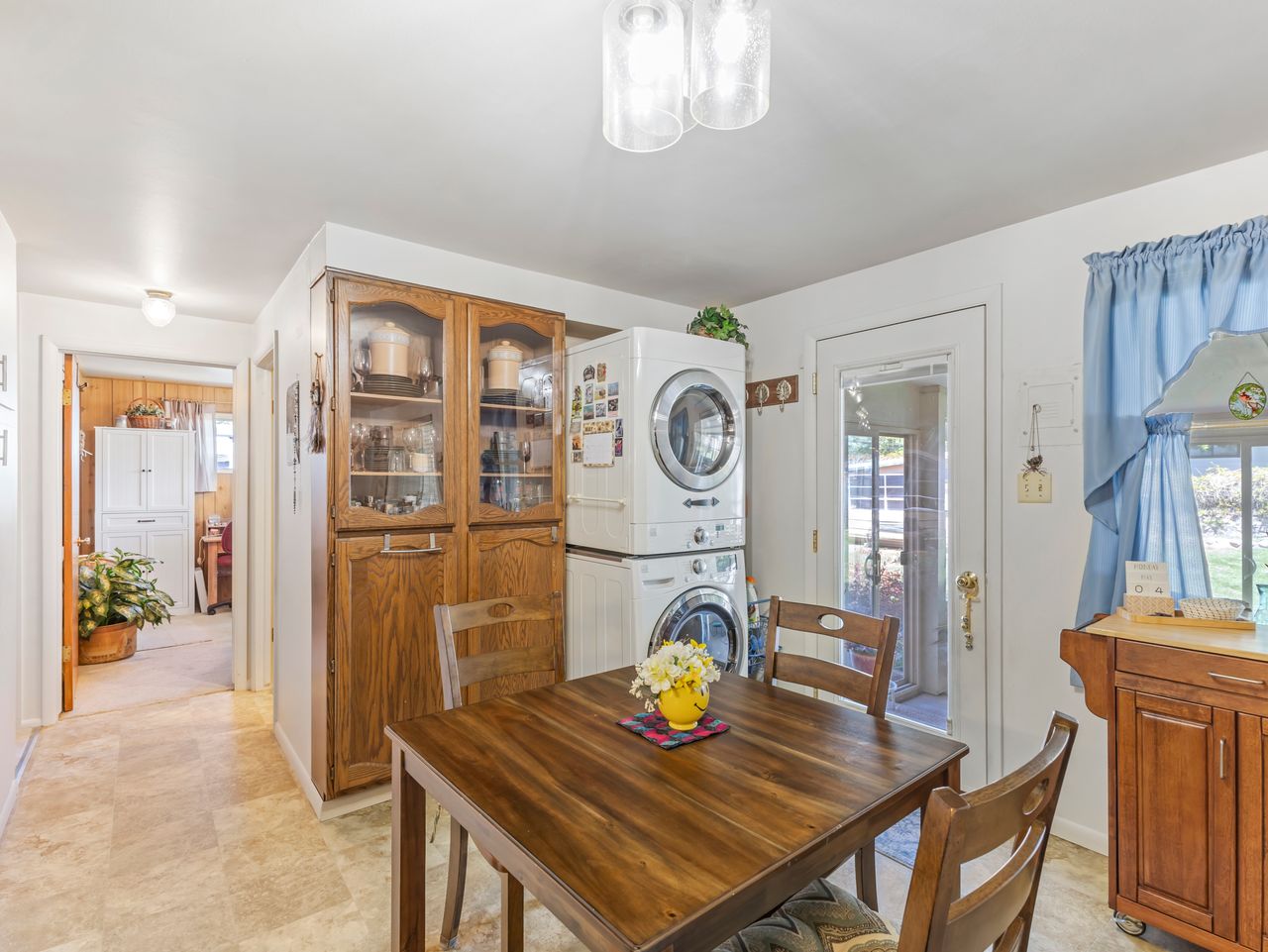 Compact dining area featuring wood-finish flooring, a built-in wood-finish display cabinet, and a stacked washer and dryer unit
