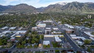 Aerial perspective of a developed urban area featuring a prominent commercial corridor, surrounding residential properties, and distant snow-capped mountains