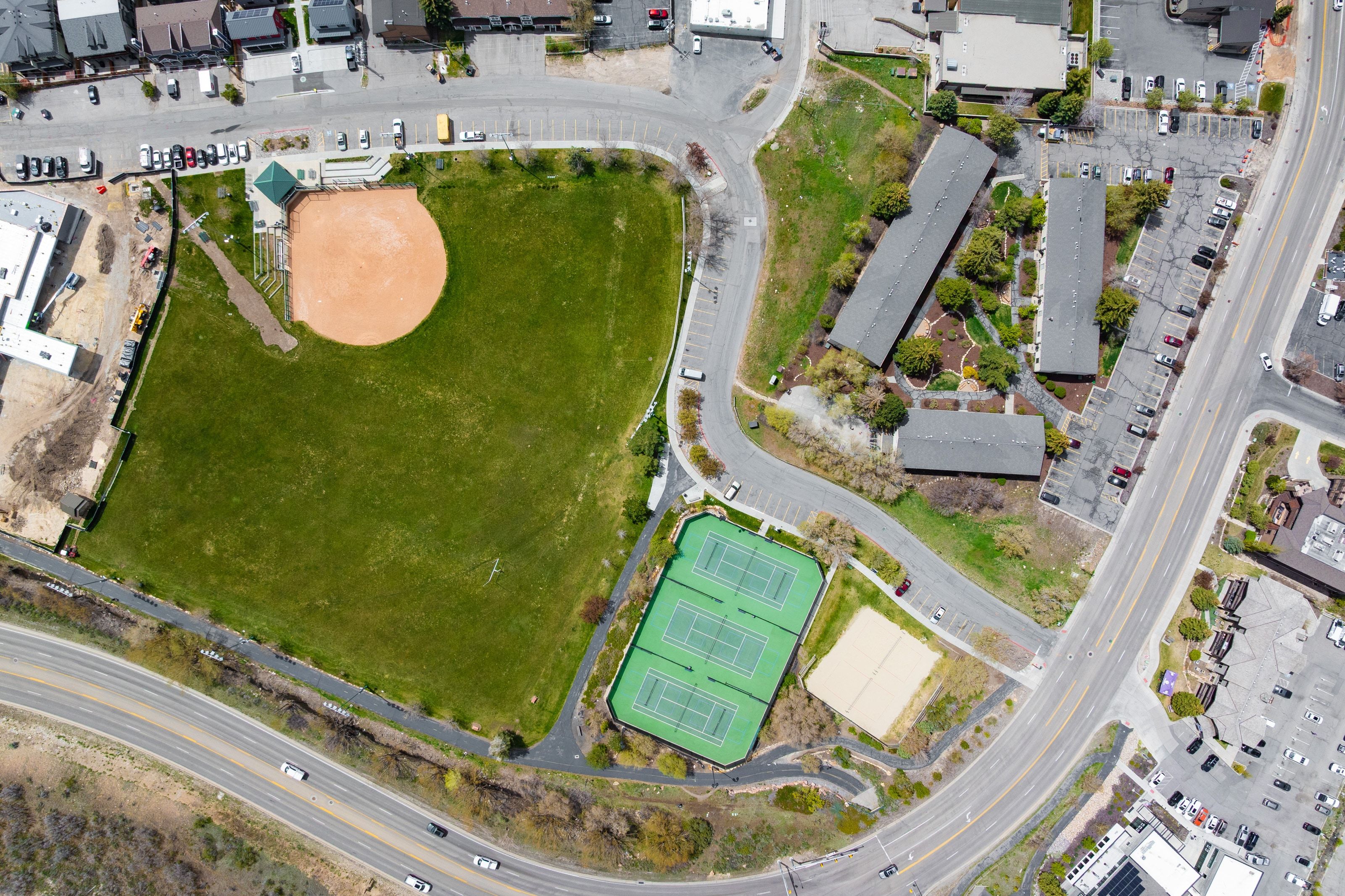 Aerial perspective showcasing a baseball field, two tennis courts, and adjacent green spaces